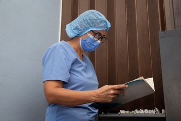 Dentist holding and reading file just taken out of the filing cabinet. Doctor looking for files in one of the drawers of the filing cabinet. 