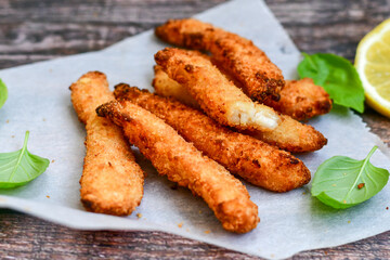 
 Crispy  deep fried   chicken strips and wedges potato. Breaded  with cornflakes chicken  breast fillets  with chilly peppers and fresh   basil on wooden rustic background