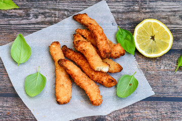
 Crispy  deep fried   chicken strips and wedges potato. Breaded  with cornflakes chicken  breast fillets  with chilly peppers and fresh   basil on wooden rustic background