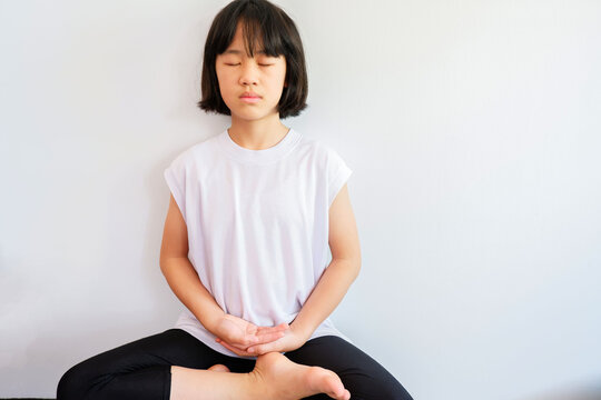 Photograph of a young woman meditating and meditating on a plastered background. with a quiet weekday