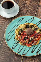 Heart waffle with pineapple and strawberry with gummy candy and ice cream on it.