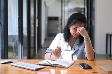 Obraz premium Stressed businesswoman sitting at her workplace in modern office.