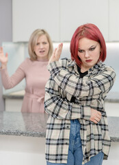 Family conflict. Angry mother screams at afraid teen daughter, girl ignoring her mom and shows stop gesture. Family relationships