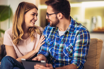 Smiling young couple using digital tablet at home
