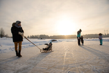 Happy family with three children having fun at ice-skating rink outdoor