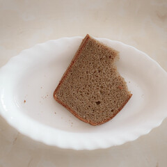 Half-eaten piece of rye bread on white plate