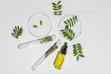 Laboratory glassware and pipette bottle with serum and oil on white background. Natural medicine,...