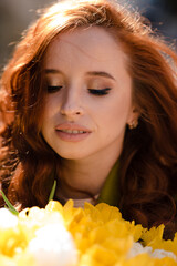 Stylish woman with red curly hair with a bouquet of yellow tulips