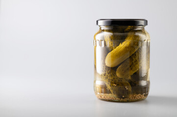 pickled cucumbers in a jar, on a light background, space for text