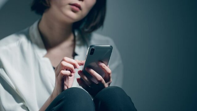 精神障害を患っている若い女性がスマートフォンを使っている