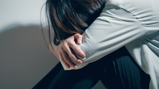 精神障害を患っている若い女性が膝を抱えている