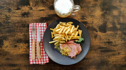 top view of a slice of roast pork with mustard on a plate with french fries