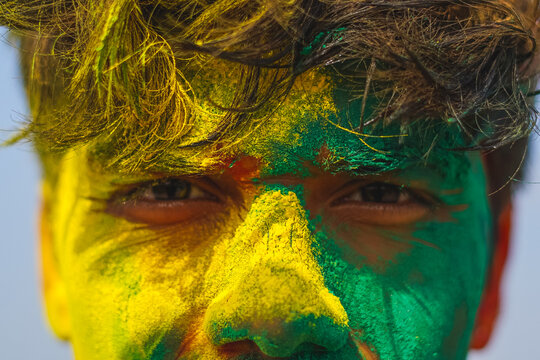 Close up portrait of a young boy covered in holi colors, young indian boy playing holi in mathura.