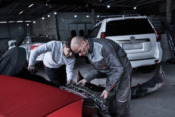 Fototapeta na wymiar Car service worker repairs restores car