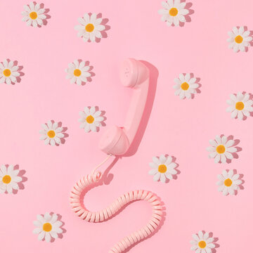 Spring creative layout with pink retro phone handset and white flowers on pastel pink. 80s or 90s retro fashion aesthetic telephone and flowers concept. Minimal romantic communication idea.