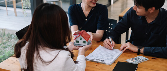 Real estate agent offer hand for customer sign agreement contract signature for buy or sell house. Happy asian couple signing a contract together at office. Real estate contact agreement concept