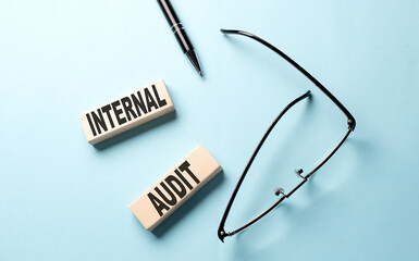 INTERNAL AUDIT text on the wooden block ,blue background