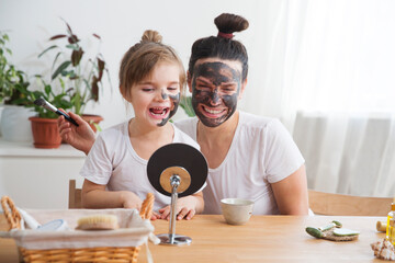 Obraz na płótnie Canvas Morning skin care. mom and little daughter have fun spending time together at home. Happy family mother and child daughter make face skin mask together. 