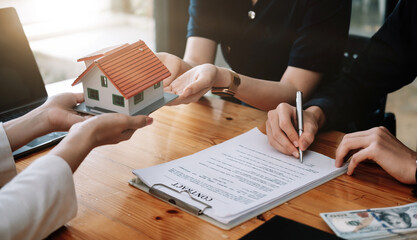 Real estate agent offer hand for customer sign agreement contract signature for buy or sell house. Happy asian couple signing a contract together at office. Real estate contact agreement concept