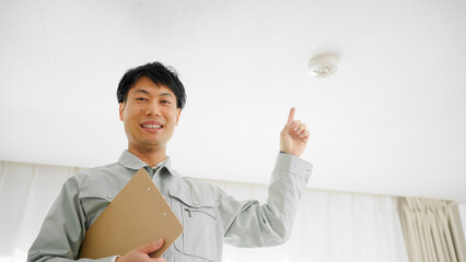 火災報知機の点検をする作業着姿の男性