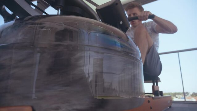 Man training in a rowing machine on the top of a building
