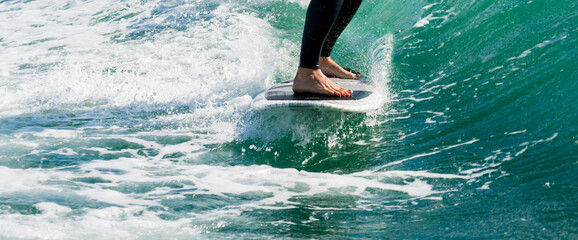 Wakeboarding. Close up of woman in wetsuit learning to wakesurfing behind wakeboard boat. Female...