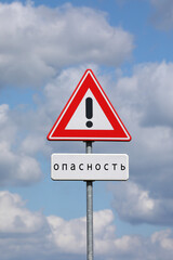 A sign with a exclamation mark warning for a dangerous situation ahead and a smaller sign below with the Russian word for danger on it