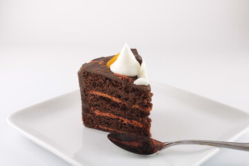 Slice of chocolate orange cake isolated on a plate isolated with copy space. Obesity concept - 490680969
