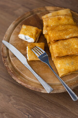Russian traditional pancakes or blini with cottage cheese and prunes on table laid for Maslenitsa holiday or carnival 