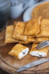 Russian traditional pancakes or blini with cottage cheese and prunes on table laid for Maslenitsa holiday or carnival 