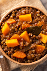 Lentil stew ragout with pumpkin and carrot in bowl on wooden table