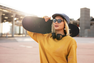 Fashion woman with skateboard. Portrait of urban young girl outdoors © Jelena