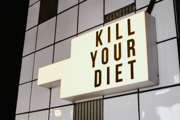 Illuminated sign on the wall indoors, saying "Kill your diet"