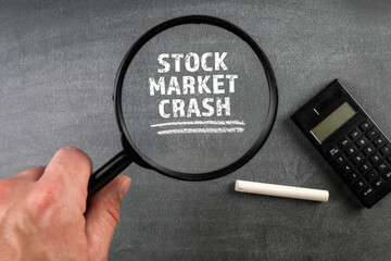 Stock Market Crash. Magnifying glass and calculator on a whiteboard background