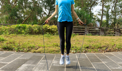 Asian woman skipping rope in park - obrazy, fototapety, plakaty