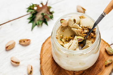 Homemade pistachio ice cream in a glass jar fresh pistachio over white background. place for text, top view