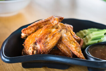 Deep fried chicken wings and green fried herb leaves, selective focus of Thai meal.