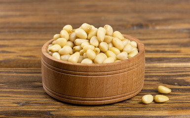 A bowl with pine nuts on a wooden background, delicious, natural. Soft focus.