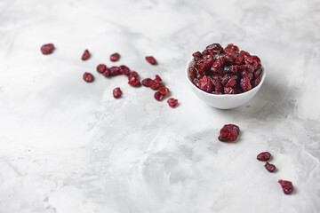 dried cranberries in a white bowl on a concrete background with a place to copy. Selective focus.