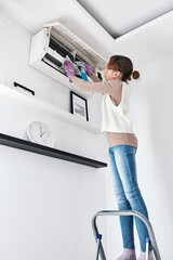 Child girl cleaning aircon filters indoor unit at home.