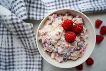 Bowl of homemade granola with yogurt and fresh berries on wooden background top view