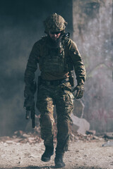 A bearded soldier in a special forces uniform walks through an abandoned building after a...