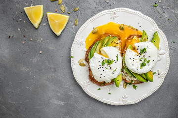 Sandwiches with avocado Poached Eggs. sliced avocado and egg on toasted bread for healthy breakfast or snack. Healthy fats, clean eating for weight loss. top view