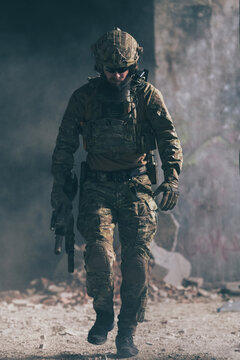 A bearded soldier in a special forces uniform walks through an abandoned building after a successful mission. Selection focus 