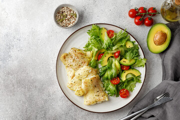 Dish with baked white fish with Frillis salad, tomatoes, avocado and seeds. Healthy fish, dinner. Top view