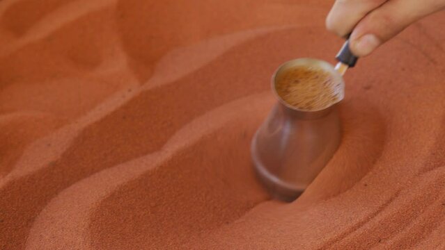 Coffee prepared on street in traditional Arabic way, cezve or ibrik (small Turkish coffe pot) is placed in red hot sand until liquid boils