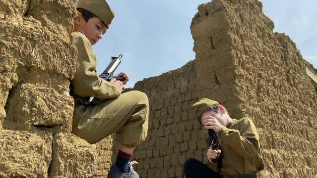 Boys in uniform of Soviet army with toy guns play soldiers