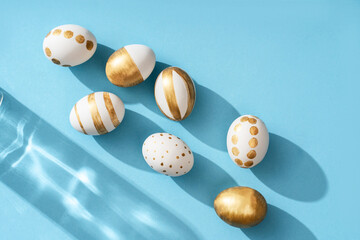 Hand-drawn Easter eggs on a blue background and beautiful shadows and glowing reflections. Flat lay background.