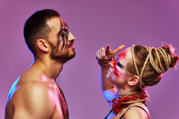 Beautiful young acrobats or gymnasts with colorful face painting on pink blue gradient background....