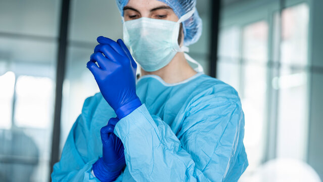 Doctor putting on protective blue gloves